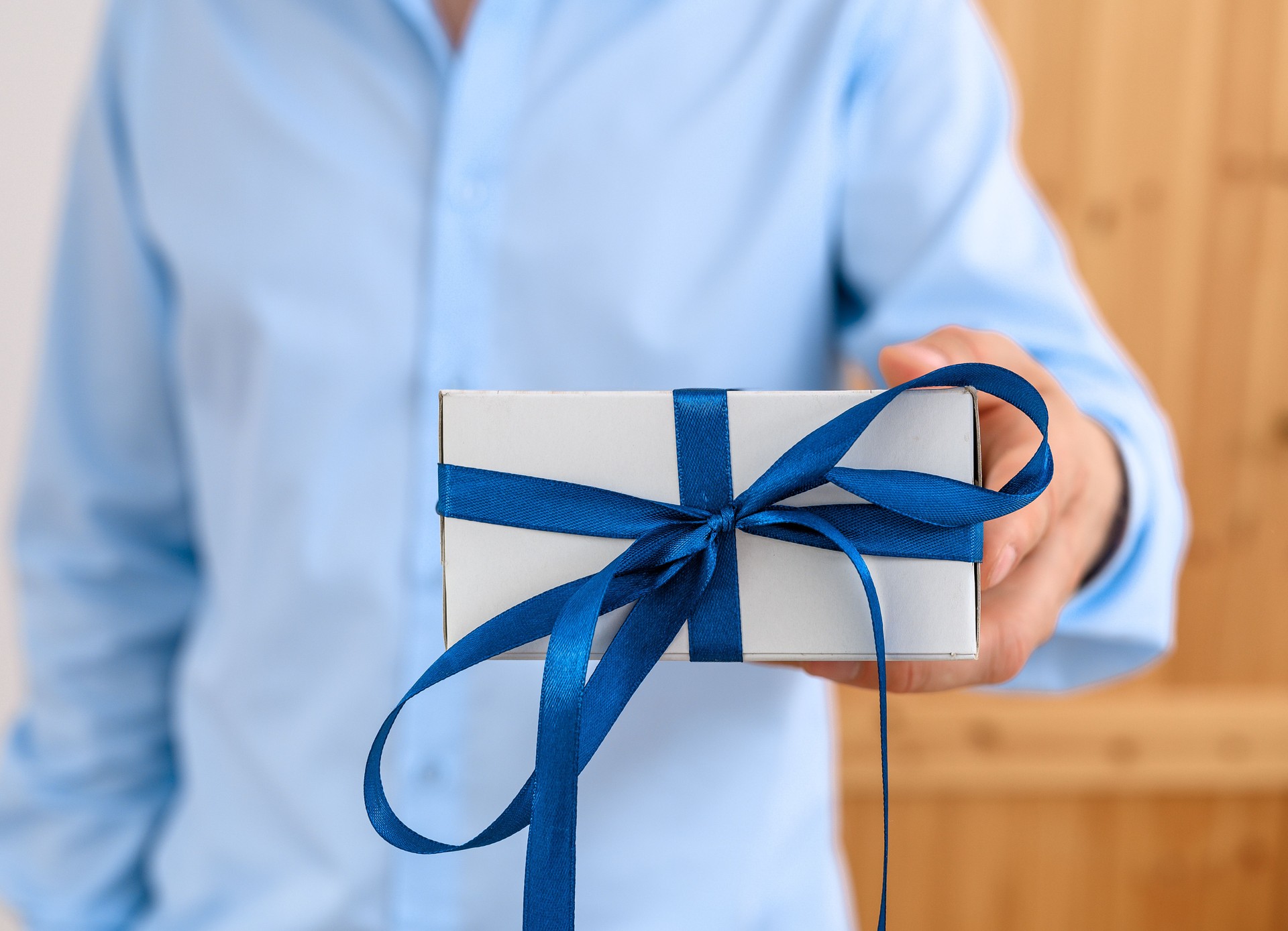 A man gives a gift, a small elegant box with a bow